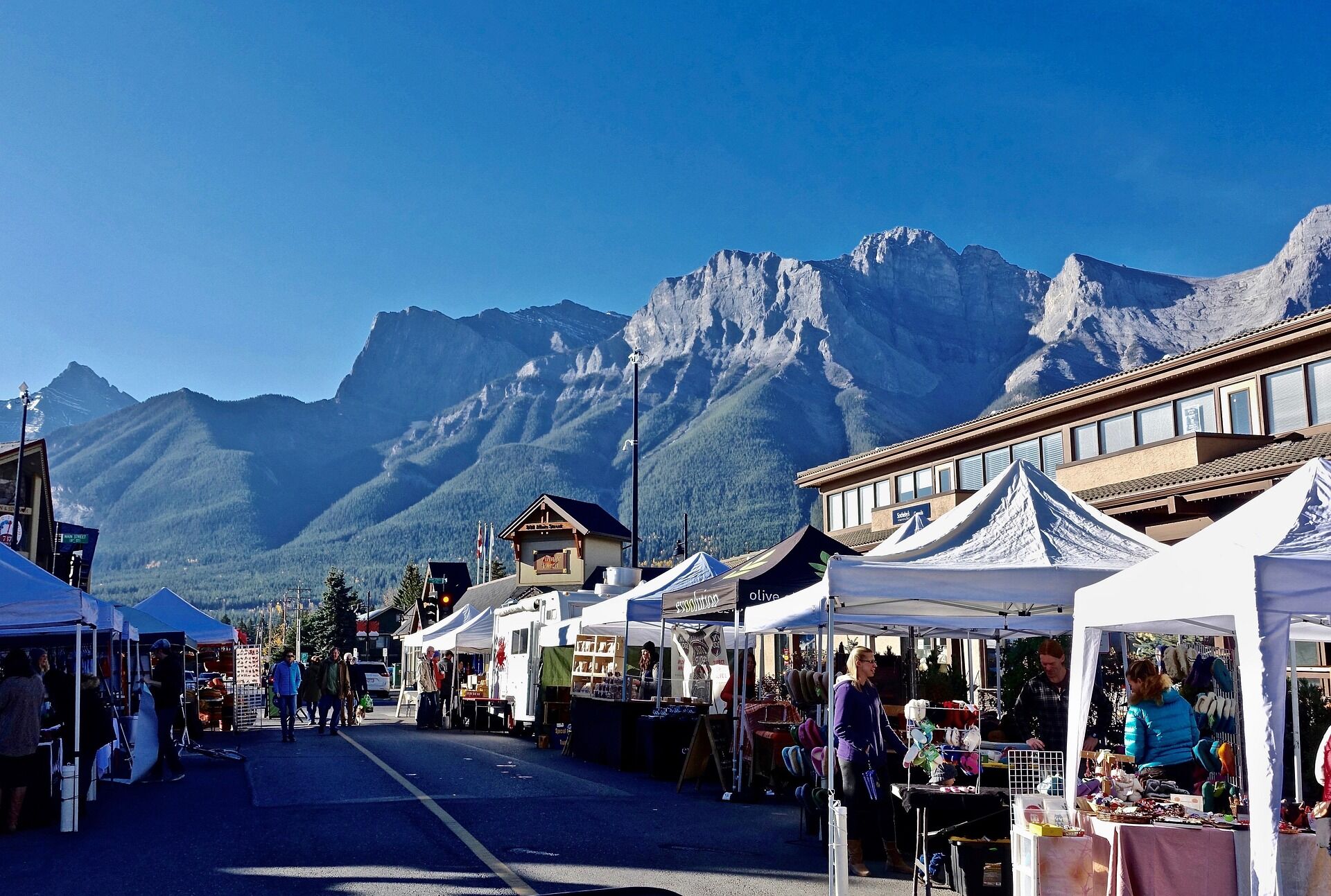Vibrant street market with vendor booths and mountains in the background
